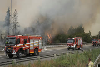 A wildfire shut the main highway linking Tel Aviv to Jerusalem on Wednesday, turning the skies over Jerusalem grey.