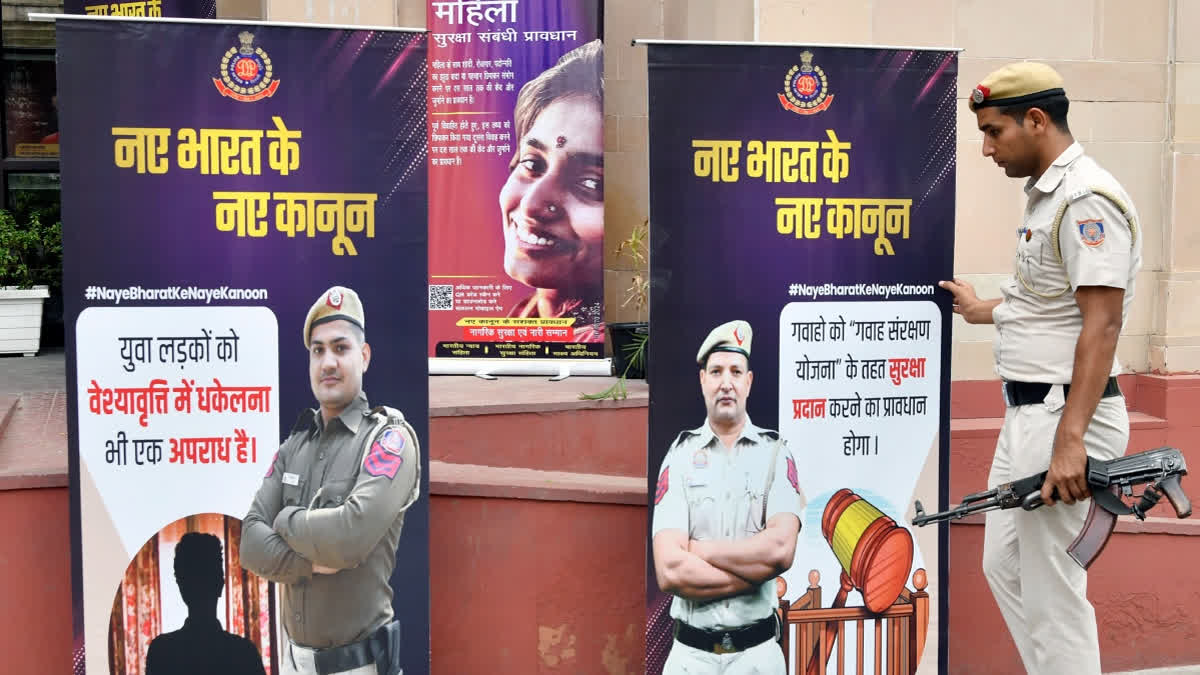Police personnel put up posters with information on new criminal laws to create awareness among people at Connaught Place in New Delhi on Monday.