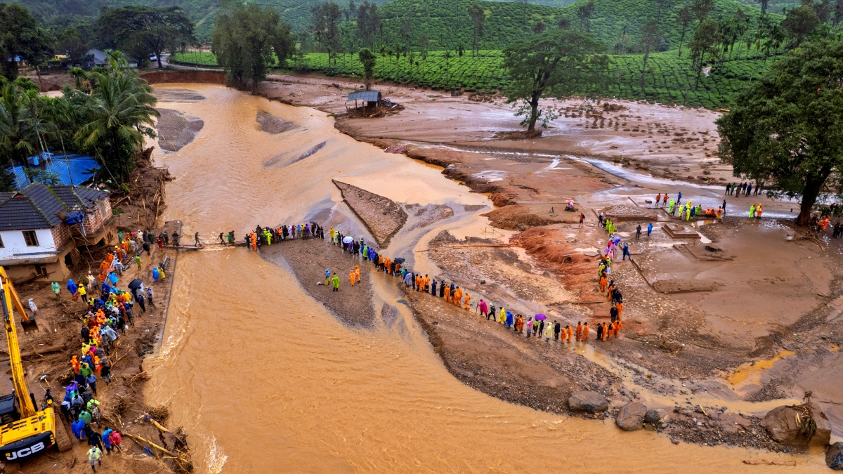 Rescuers on their second day of mission following Tuesday’s landslides cross a river at Chooralmala, Wayanad district in Kerala.