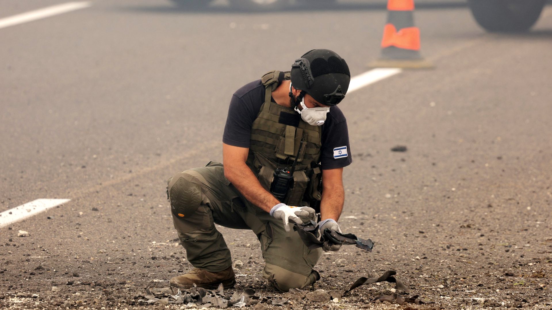 A member of Israeli security forces inspects the impact site of a reported rocket fired from Lebanon, on the Horeshim interchange in central Israel on October 1, 2024. Air raid sirens sounded in central Israel on October 1 and an AFP journalist heard explosions in the city of Tel Aviv, with the military saying projectiles had been fired from Lebanon. Police said one projectile hit a road near the central town of Kfar Kassen, wounding a man who was struck by shrapnel and treated by emergency services.