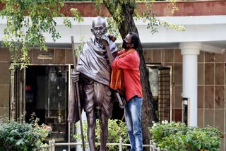 A worker cleans the statue of Mahatma Gandhi on the eve of Gandhi Jayanti at Rajghat in New Delhi