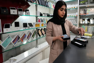 A cellphone vendor works at her shop in downtown Tehran, Iran