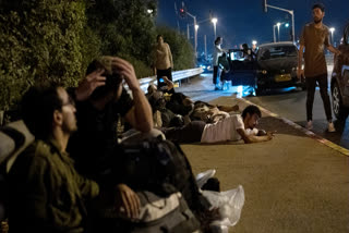 Israelis take cover as projectiles launched from Iran are being intercepted in the skies over in Rosh HaAyin, Israel, Tuesday, Oct. 1, 2024.