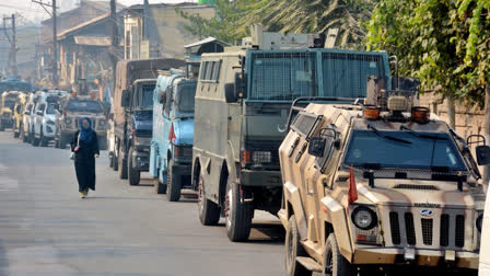 A woman walks past the security vehicles parked during a search operation after reports of movement of terrorists in the Khanyar area, in Srinagar, Saturday, Nov. 2, 2024.