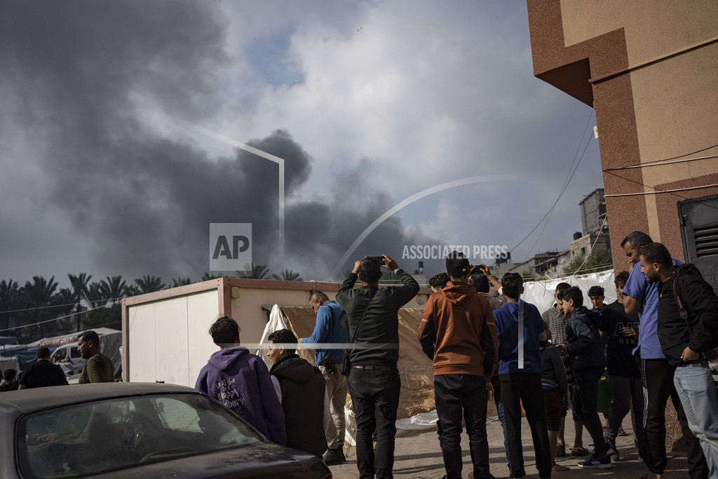 Palestinians look at smoke following an Israeli airstrike in Khan Younis, Gaza Strip