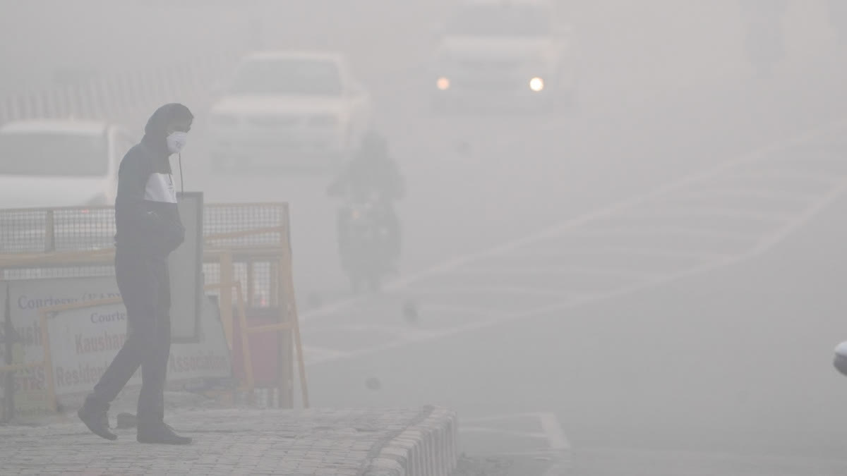 A man crosses a road amid dense fog in New Delhi on Wednesday