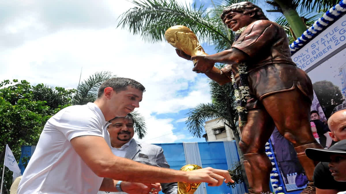 FIFA World Cup 2022 winner Argentinian footballer Emiliano Martinez pays tribute to the statue of Diego Maradona during his visit in Kolkata. (IANS photo)