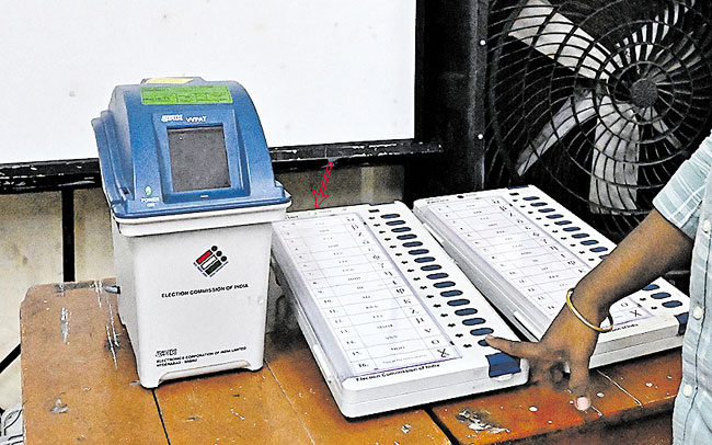 A polling officer shows how to vote on EVM