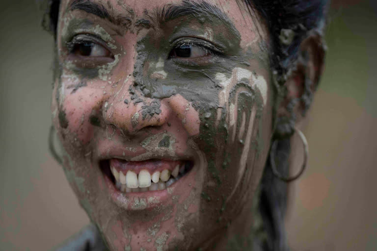 A girl rests while playing with the mud in a paddy field during Asar Pandra, or paddy planting day at Bahunbesi, Nuwakot District, 30 miles North from Kathmandu, Nepal, Friday, June 30, 2023. (AP)