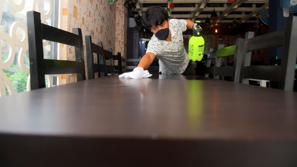 Restaurant worker cleaning the table of the restaurant after the government eased a lockdown imposed as a preventive measure against the COVID-19 coronavirus, in Agartala on Tuesday.