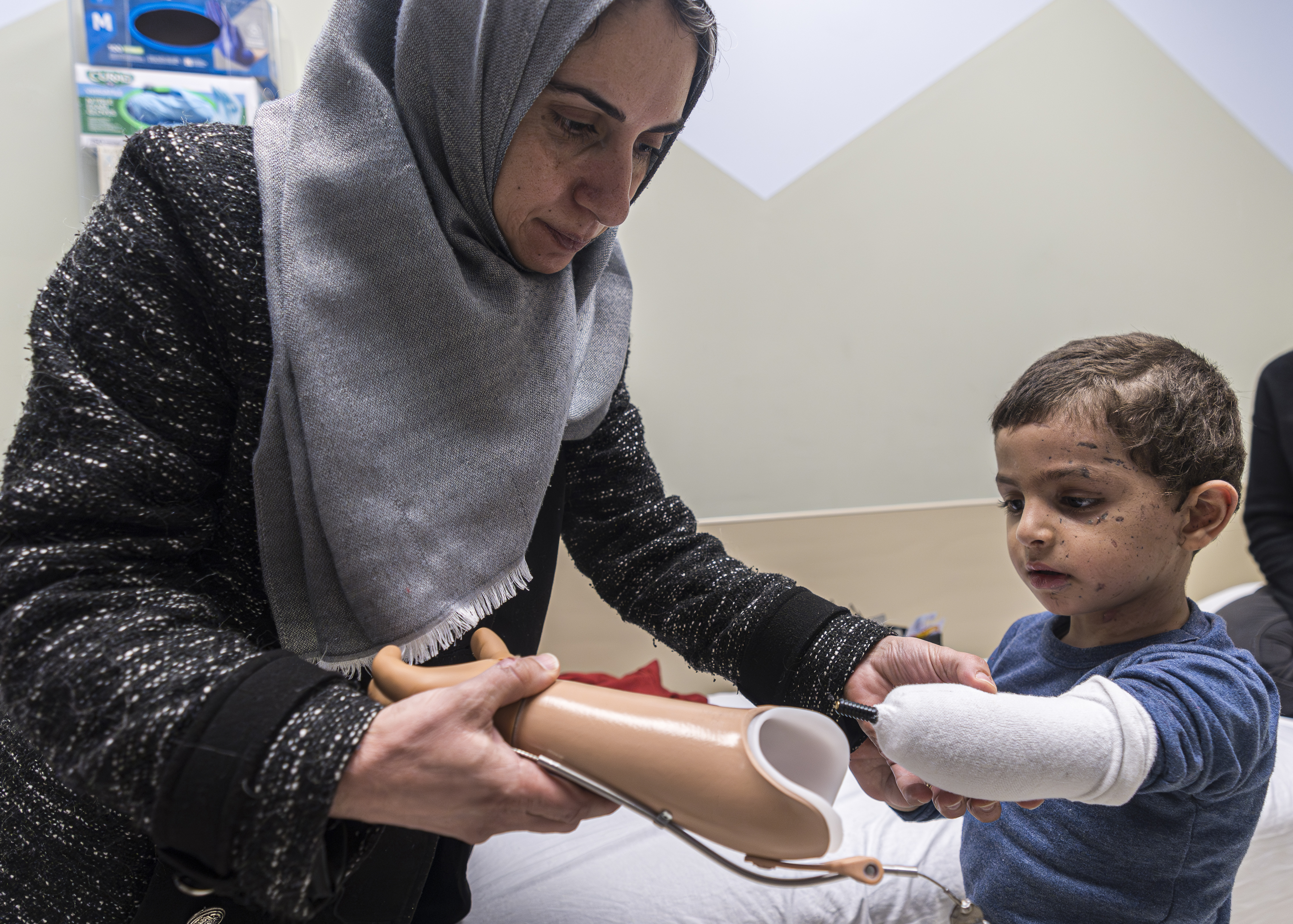 Maha Abu Kuwaik helps her nephew, 4-year-old Omar Abu Kuwaik, attach his new prosthetic arm at Shriners Children's Hospital on Wednesday, Feb. 28, 2024, in Philadelphia.