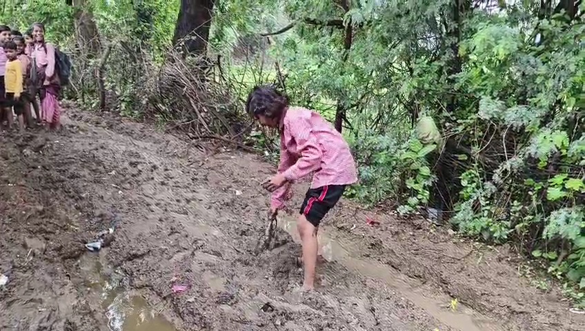 कीचड़ में फंसी चप्पल निकालती बच्ची.