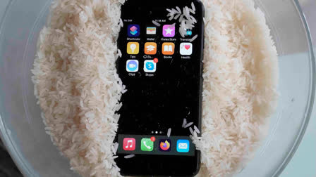 A view of a wet smartphone placed in a bowl of rice to dry, in London, Wednesday, Feb. 28, 2024