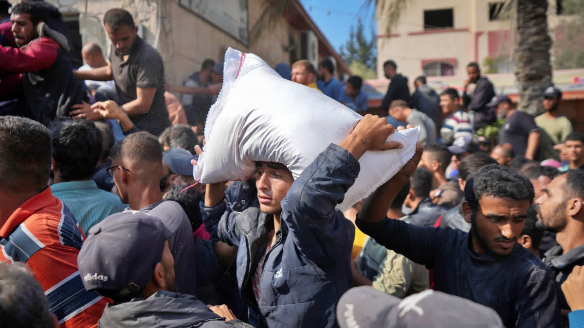 Palestinians gather to receive bags of flour distributed by UNRWA, the U.N. agency helping Palestinian refugees, in Deir al Balah, central Gaza Strip, Saturday, Nov. 2, 2024.