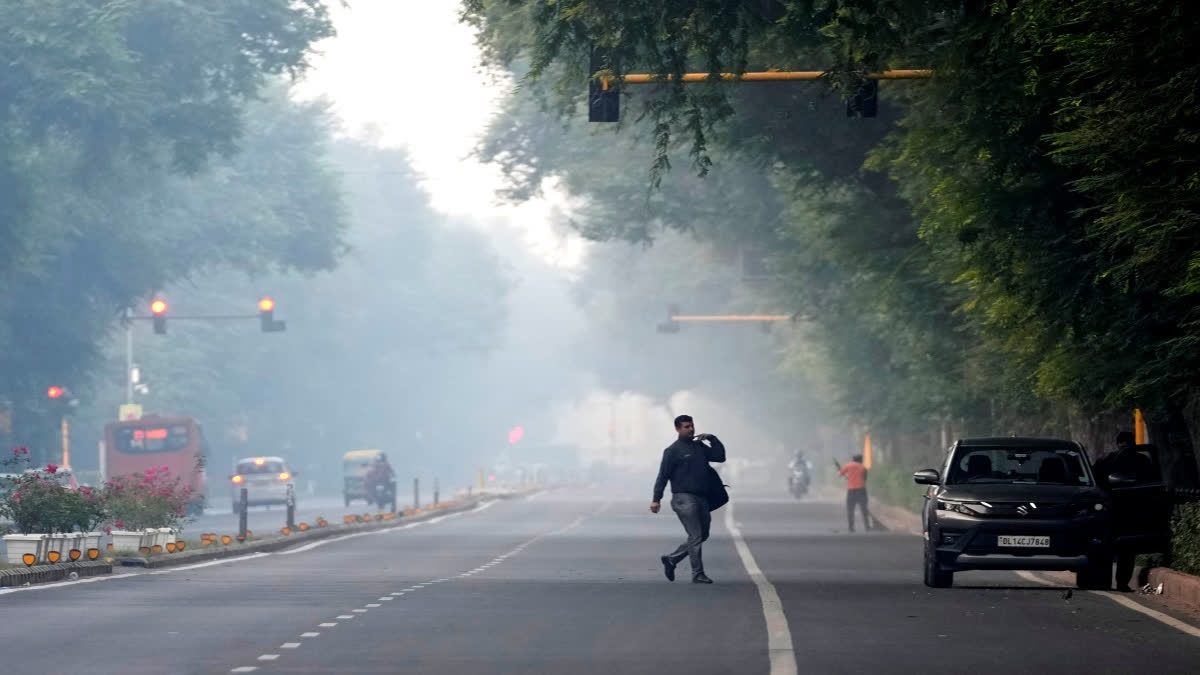 A man crosses a road in the early morning smog the day after the Hindu festival Diwali, in New Delhi