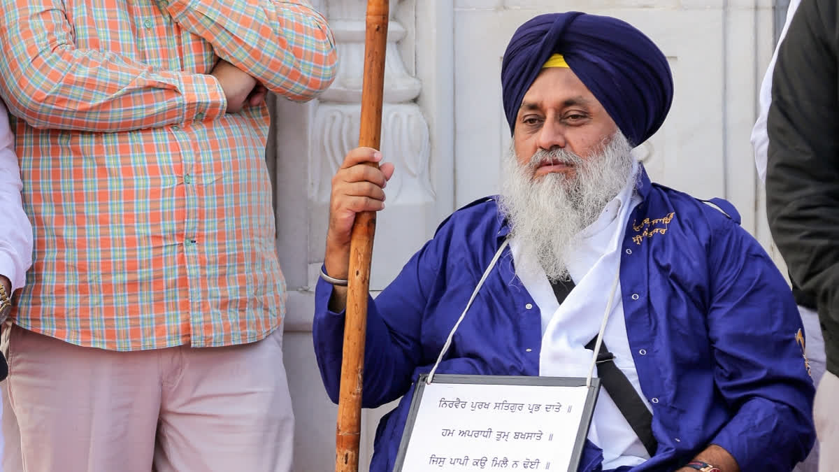 Former Punjab Deputy Chief Minister Sukhbir Singh Badal sits on a wheelchair with a plaque around his neck and performs sewadar (guard duty) following the religious punishment pronounced for him by Sri Akal Takht Sahib, at the entrance of the Golden Temple in Amritsar on Tuesday.