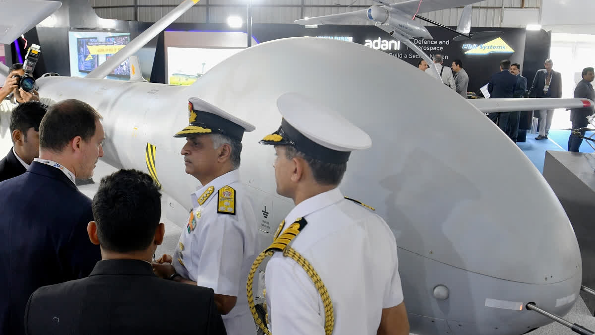 Vice Admiral of the Indian Navy G. Ashok Kumar (2R) speaks with representatives of Adani Defence and Aerospace standing next to a Hermes 900 Unmanned Aerial Vehicle (UAV) during his visit to their stall in the exhibition area on the third day of the five-day Aero India 2019 Airshow at the Yelahanka Air Force Station in Bangalore