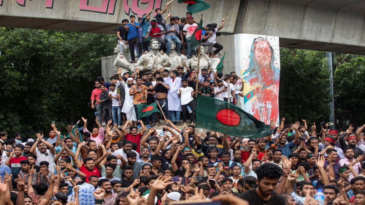 Protesters climb a public monument as they celebrate after getting the news of Prime Minister Sheikh Hasina's resignation in Dhaka.