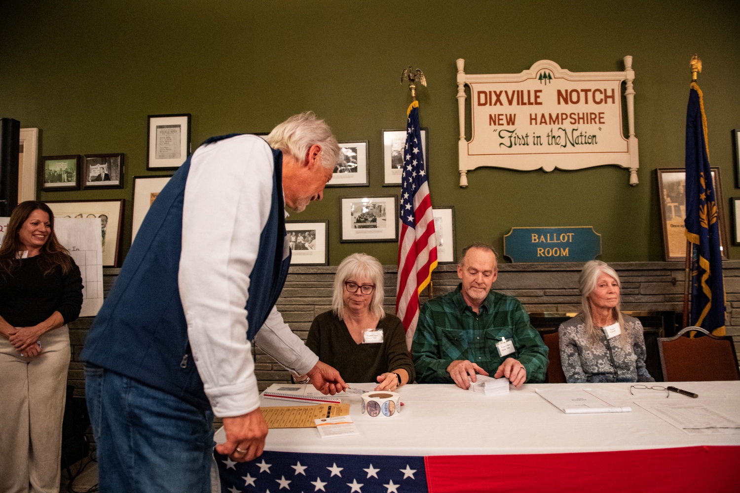 A resident of Dixville Notch shows their ID as they check in to cast their ballots in the US election at midnight in the living room of the Tillotson House at the Balsams Grand Resort, marking the first votes in the US election, in Dixville Notch, New Hampshire on November 5, 2024. The six people voting in Dixville Notch, four Republican and two undeclared, kick off Election Day at the stroke of midnight.