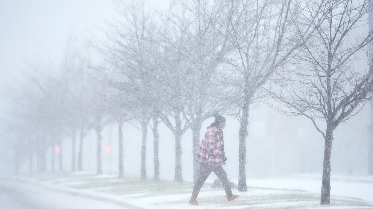 A person crosses a street as heavy snow falls Sunday, Jan. 5, 2025, in St. Louis.