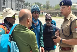 A police official interacts with the trekkers, who were trapped on the Sahastratal trek route, after they were rescued by the SDRF team, on Wednesday. Six trekkers were rescued by the SDRF.