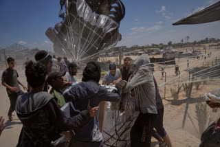 Palestinians rush to collect humanitarian aid airdropped by parachutes into Deir al-Balah, central Gaza Strip, Tuesday, Aug. 5, 2025.