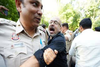 A police personnel dragging out a protestor during the scuffle