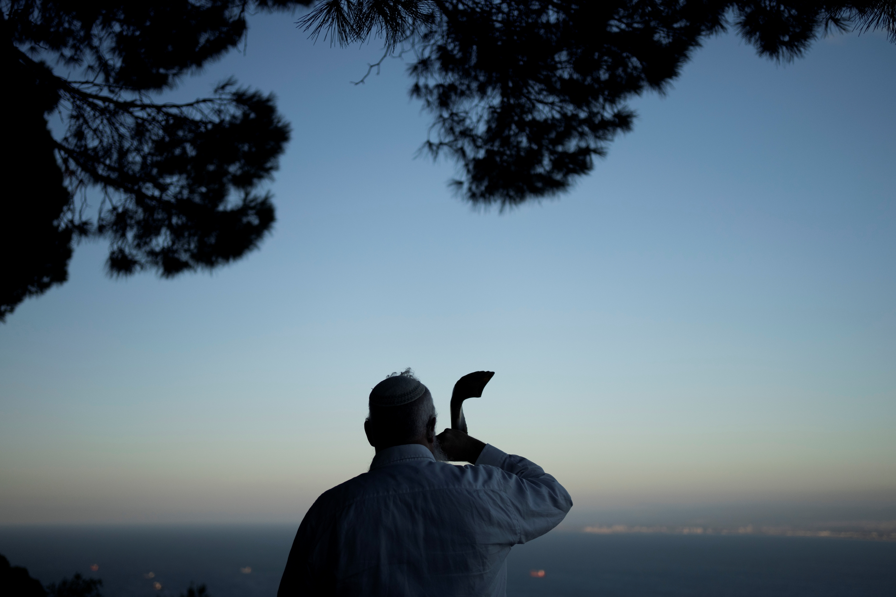 A man blows a shofar, a ram's horn, marking Rosh Hashanah, the Jewish New Year, overlooking the port of Haifa, Israel, Friday, Oct. 4, 2024