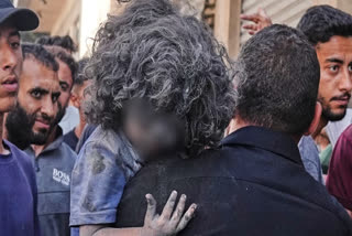 اسرائیلی حملے کے بعد فلسطینی شخص ایک زخمی بچے کو لے جاتے ہوئے