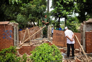 A man peeks inside the boundary wall of the vandalised house of Sheikh Hasina, who resigned as Prime Minister on Monday, in Dhaka, Bangladesh, Tuesday, Aug. 6, 2024.