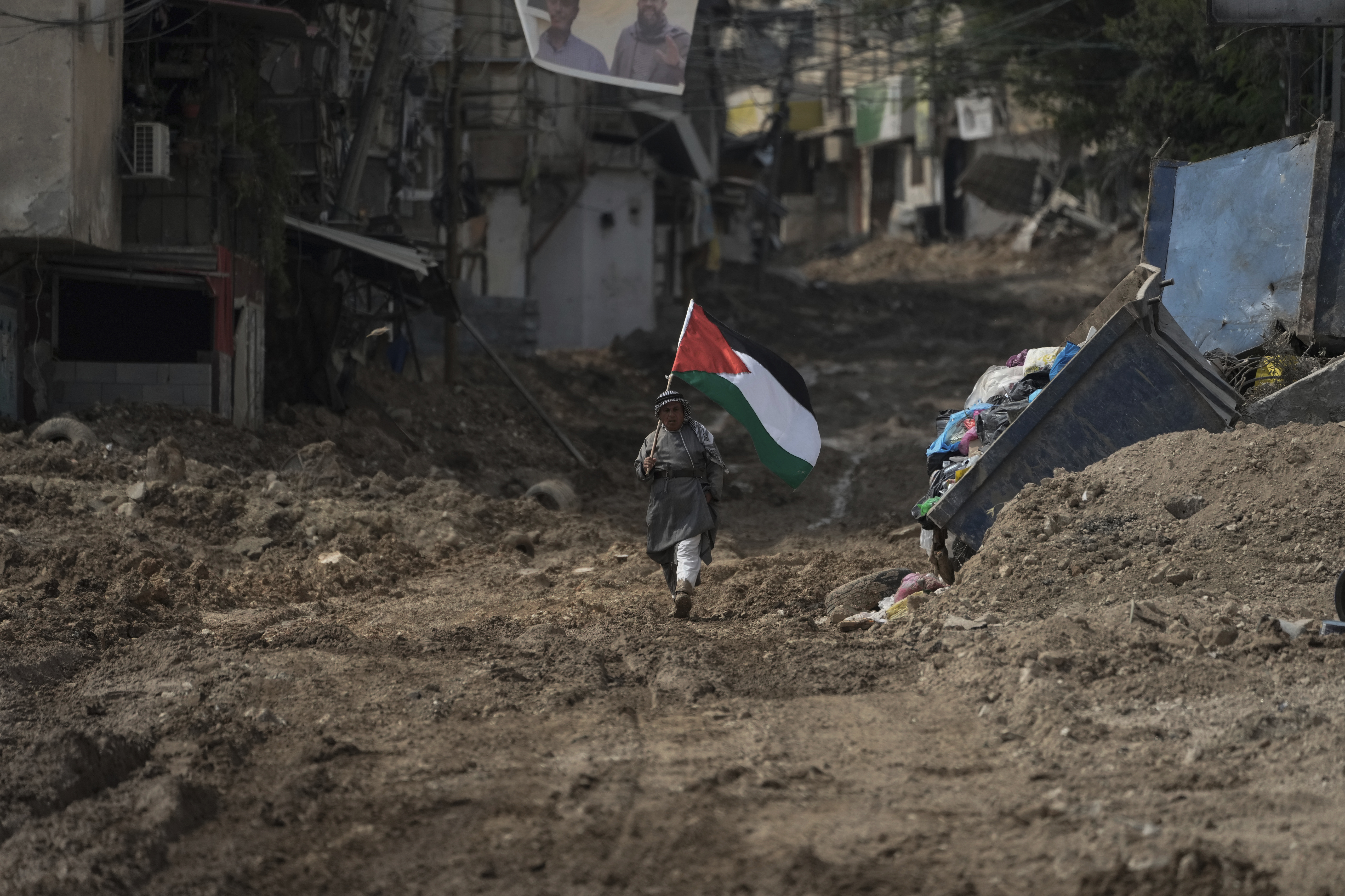 ایک فلسطینی تباہ شدہ غزہ میں فلسطین کا پرچم تھامے آگے بڑھ رہا ہے