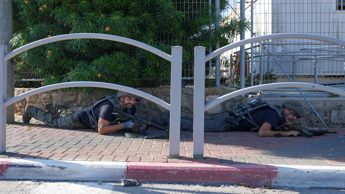 Israeli security forces take cover during rocket attack siren warning as rocket fired from the Gaza Strip, in Ashkelon, southern Israel, Saturday, Oct. 7, 2023 (AP photo)