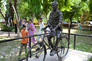 Visitors walk past a statue of Mahatma Gandhi inside a park on the eve of Gandhi's birth anniversary, in New Delhi