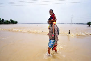 A man carrying his daughter on his shoulders in the flood-affected area of ​​Jamunamukh in Hojai.