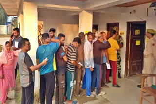 Voters queue up outside a polling station to cast vote during JK assembly elections