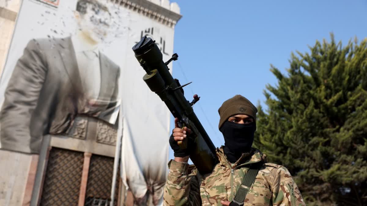 File photo of an anti-government fighter holds a weapon as he keeps position near a defaced portrait of Syrian President Bashar al-Assad, in the city of Hama after forces captured the central Syrian city, on December 6, 2024.