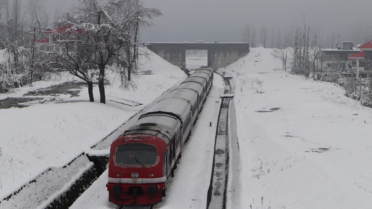 A train passes through a snow-covered railway track during the fresh snowfall in Qazigund