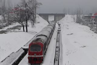 A train passes through a snow-covered railway track during the fresh snowfall in Qazigund