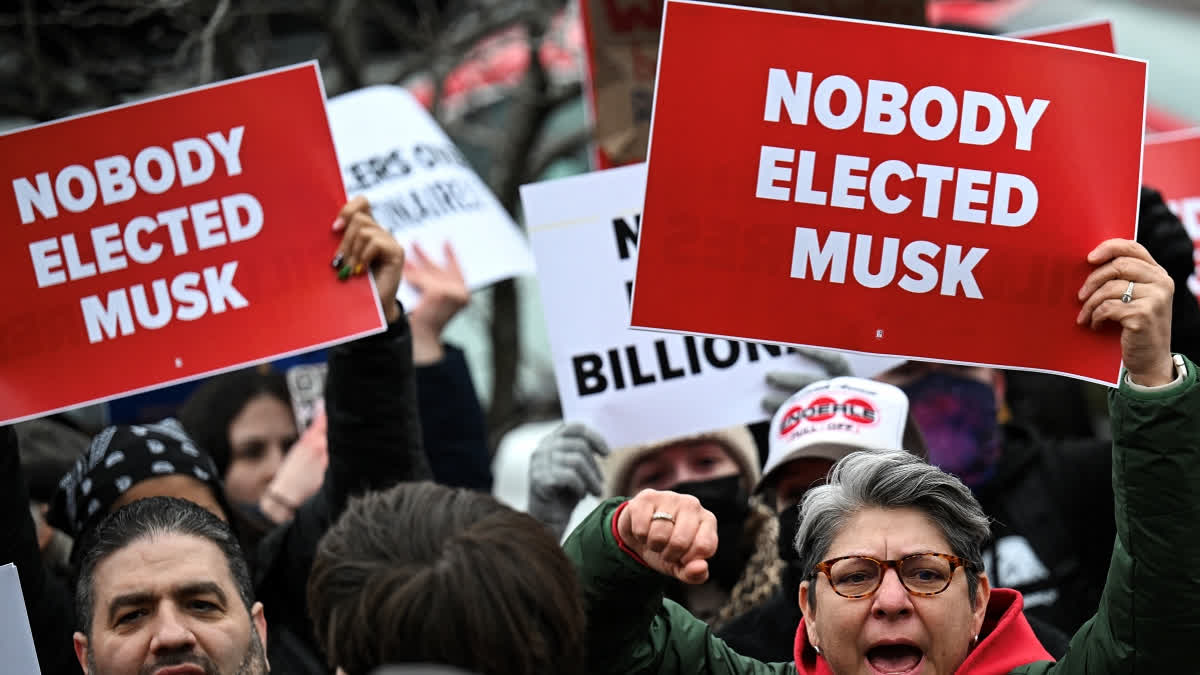 People hold up signs as they protest against US President Donald Trump and Elon Musk's "Department of Government Efficiency" (DOGE) outside of the US Department of Labor near the US Capitol in Washington, DC, February 5, 2025.