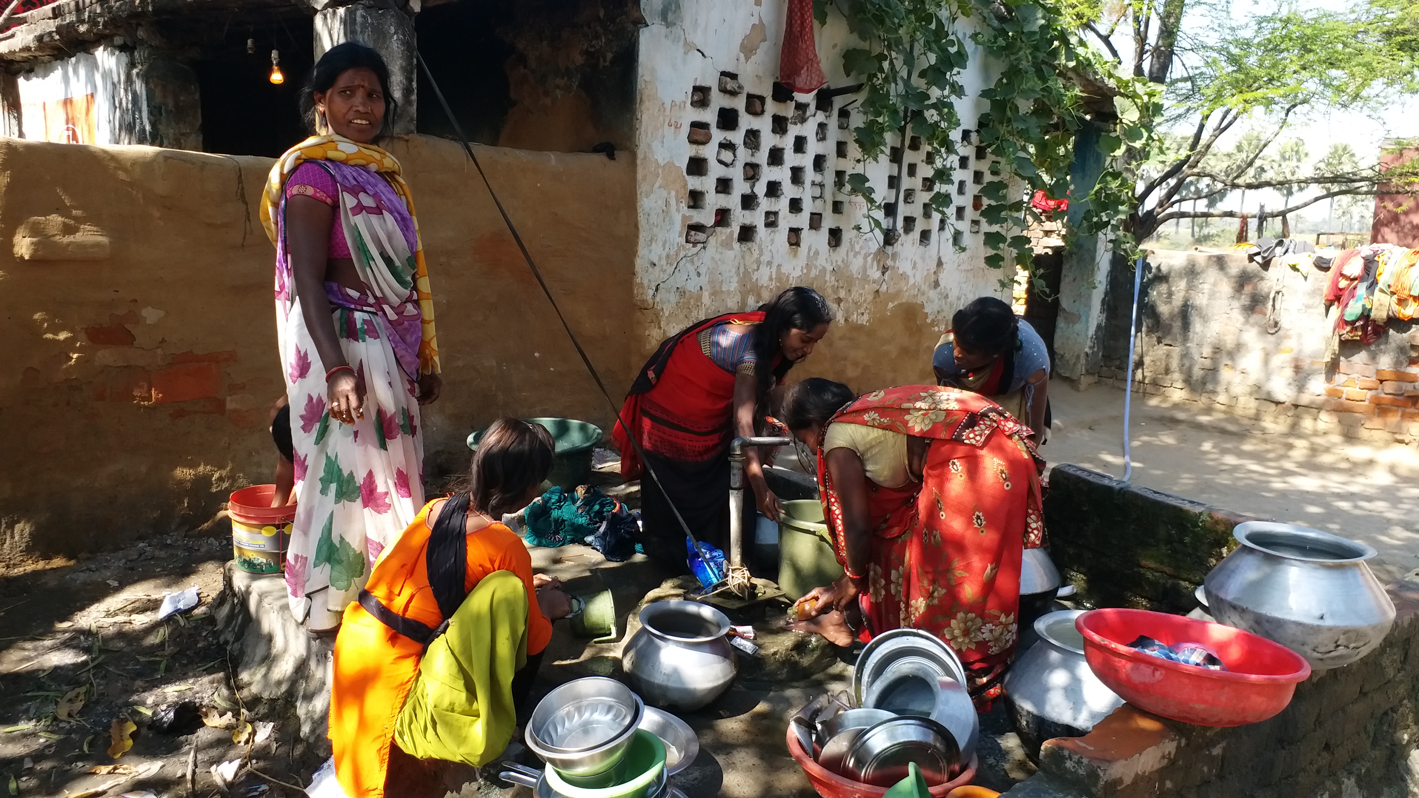 Village women collect water from a tap.