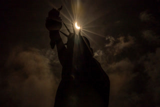 The moon partially covers the sun behind the Statue of Liberty during the a solar eclipse on the Liberty Island, Monday, April. 8, 2024, in New York.