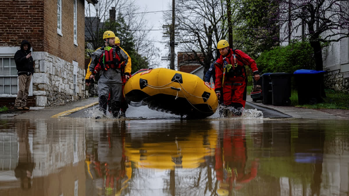 Search and rescue firefighters carry a boat to a flooded neighborhood on Sunday, April 6, 2025, in Frankfort