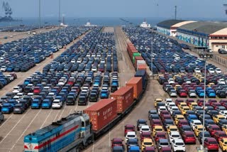 A cargo train moves past new cars waiting for shipment in a port, in Yantai in east China's Shandong province on Wednesday, May 7, 2025. (AP)