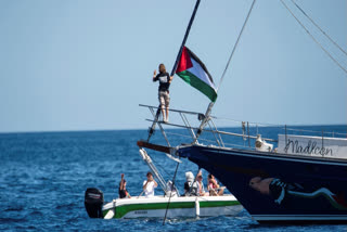 Climate activist Greta Thunberg stands near a Palestinian flag after boarding the Madleen boat and before setting sail for Gaza along with activists of the Freedom Flotilla Coalition, departing from the Sicilian port of Catania, Italy, Sunday, June 1, 2025.