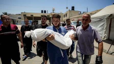 A Palestinian man holds the body of a child killed in the Israeli bombardment of the Gaza Strip, at a hospital morgue in Deir al-Balah, Tuesday, July 9, 2024.