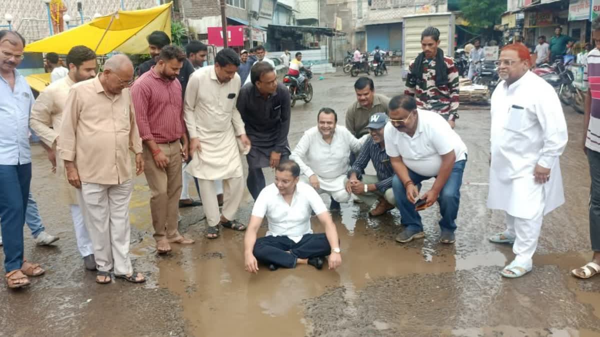 EX MLA SITS ON POTHOLE