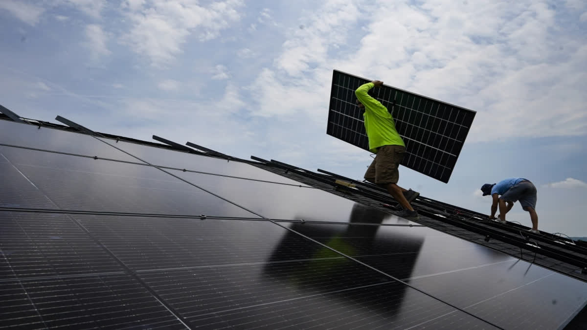 Nicholas Hartnett, owner of Pure Power Solar, carries a panel as he and Brian Hoeppner, right, install a solar array on the roof of a home in Frankfort, Ky., July 17, 2023. (AP Photo/Michael Conroy, File)