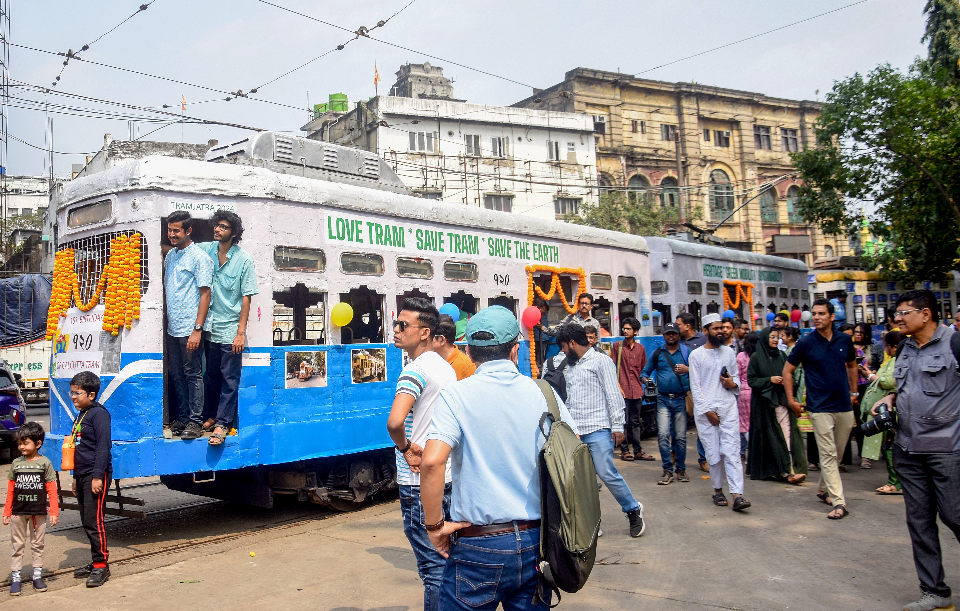 A decked up tram being boarded by enthusiasts in Kolkata