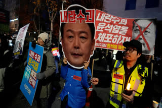 A participant wearing a mask of South Korean President Yoon Suk Yeol attends a rally demanding his impeachment outside the National Assembly in Seoul, South Korea, Sunday, Dec. 8, 2024.The signs read "Arrest Yoon Suk Yeol."