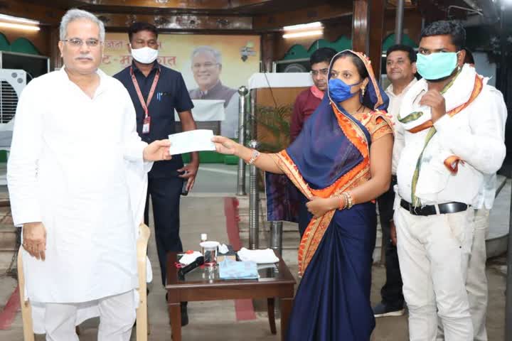 Sarpanch handing over check to CM